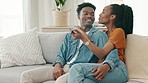 Love, movies or film and couple watching TV on sofa in their living room apartment or home on the weekend. Happy woman, guy or black people hugging on couch with romantic television show in lounge 