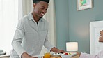 Black couple, anniversary and breakfast in bed with a romantic man spoiling a happy woman with love and food on her birthday or honeymoon. Lovers, bedroom and hotel stay in a healthy relationship