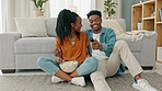 Happy black couple, eating popcorn and a movie playing in the living room of their home or house. Love, romance and man and woman having leisure time while looking at tv and browsing channels.