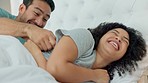 Bedroom fun, laugh and silly couple lying in bed and being playing and enjoying free time together. Man tickling and teasing woman while enjoying lazy morning, honeymoon love and weekend at home