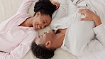 Happy black couple bonding in bed, talking, relax and laughing together in a bedroom. Above young man and woman sharing a loving, romantic moment and enjoying a conversation and relationship indoors