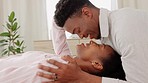 Happy, love and couple in a bedroom kiss and laughing in happiness, bonding time together at home. Young black man and woman kissing on a bed with a smile in joy for caring relationship and marriage