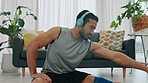 Headphones, music and fitness stretching man in living room apartment with a motivation or wellness podcast. Young guy on floor doing workout training or exercise muscle legs and listening to audio