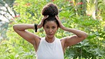 Natural beauty, hair and environment with a beautiful woman fixing her bun while standing outside in nature surrounded by green trees and fresh air. Portrait of Brazilian female outside for wellness