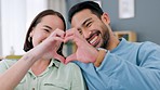 Love and hands of couple doing heart sign while happy, smile and relax on home living room sofa. Partnership, trust and man and woman bond together during quality time and form emoji icon with hand
