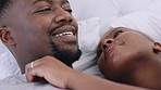 African couple talking on bed in morning, love during funny conversation in bedroom in house and happy black people with smile during chat in home. Face of man and woman in discussion in apartment