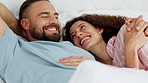 Relax, love and funny couple in bed together in the morning in home, house or bedroom. Smile, happiness and romance of intimate man and woman laughing at a joke, humor or playful cuddle on holiday.