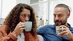 Happy couple, love and coffee while sitting in the living room at home to relax and spend time together. Married man and woman bonding while drinking hot beverage and sharing laugh and communication