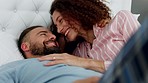 Love, couple and kiss in bed with a man and woman lying in the bedroom of their home together. Smile, happy and romance with an affectionate husband and wife sharing an intimate moment in their house