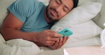 Good morning, text and wake up with man smiling on his phone in bed reading happy message, social media or app. Online, communication and good news with young male lying in bedroom at home