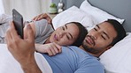 Couple in bed with smartphone for meme, social media online content or notification and laughing together cuddling or hugging in bedroom. In love man and woman on cellphone home wifi on the weekend
