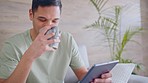 Technology, tablet in man hand, drinking tea or coffee, on social media and with smile in living room. Digital, tech or smartphone with male laughing and watching video on web, internet or online app