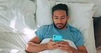 Man in bed with phone or smartphone for communication  on social media message app or watch internet videos. Young morning person in home bedroom texting on 5g wifi technology mobile online cellphone