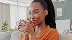Black woman with cup of coffee in hand, smile on sofa relax or take break in her home. Young African American lady, at peace to smell tea or hot chocolate with happiness on face in living room.