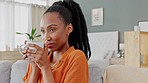 Coffee break, relax and woman on sofa in her apartment enjoying her day indoor with cup in hands. Calm, self care and self love black woman drinking espresso or tea on a couch in living room or home