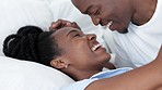 Happy African couple in bed, talk and smile have silly conversation in morning on holiday or at their house. Black woman and man relax laugh, at funny joke in bedroom while home or on vacation.