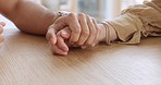 Love and hands of couple together in support, help and comfort or hope for the future. People, family or man and woman holding hands in life partnership, trust and unity on wooden table or desk