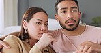 Scared couple, watching tv and eating popcorn with horror film in the living room in house, jump at television show and surprise at movie in home. Asian man and woman with cinema night together
