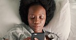 Woman with phone, in bed and online in the morning, scrolling though social media, messages and texting. Black woman looking at smartphone, in pajamas and laying in bed. at home in her bedroom