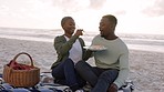 Sushi, beach and picnic couple dating or on romantic honeymoon date with ocean, sea and sky. Happy, love and romance woman and man or black people eating food together for valentines day anniversary