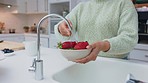 Woman cleaning strawberry, with water and hands to take dust, dirt or bacteria off for energy in diet. Lady in home kitchen, washing red fruit in bowl for healthy snack, salad or smoothie