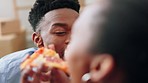 Lovers, laughing and eating pizza. Two, cheerful young happy black African couple, clutching arms and eating pizza smiling at each other, being goofy over lunch, being affectionate 