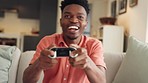 Gaming, winner and relax with black man gamer with video game controller sitting on his sofa in his living room at home. Success, celebration and esports with young male playing  on console