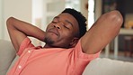 Relax, tired and black man sitting on a sofa to take a nap in the living room in his house. Comfortable, calm and happy african guy leaning and resting on a couch alone in his peaceful modern home.