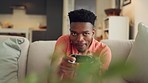 Online gaming, streaming and black man playing a video game while relaxing in his living room. Entertainment, tv and african cyber gamer with energy and freedom sitting on the sofa in his home.