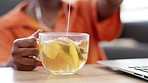 Lemon tea, hot beverage and freelance woman dipping her teabag in a cup for health while sitting at home. Drink, relax and hands of female on a detox wellness diet or making a remedy for cold and flu