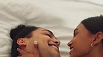 Young couple kiss and hug on bed happy to be together at home. Love life, romance and intimacy with Indian woman and man or people relax in their bedroom or apartment for valentines day or honeymoon