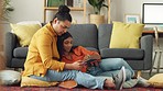 Happy couple together, use a tablet on living room floor, relaxing at their apartment home. Digital innovation, 5g technology and streaming tech allows people to find online entertainment at any time