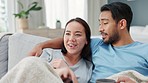 Couple, tv remote and television with coffee in living room watching comic funny comedy movie, online streaming service or video. Relax, love and cozy man and woman watch film on couch or sofa.