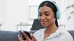 Music, dance and phone with a woman streaming audio on wireless headphones while on her sofa to relax at home on the weekend. Radio, freedom and wifi with a happy young female enjoying free time