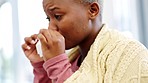 Sick, cold and tissue with black woman in blankets blowing her nose while sitting on her sofa in her living room at home. Healthcare, virus and allergy with young female suffering from illness or flu