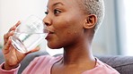 Glass of water, hydrate and happy drinking woman thirsty on the couch or in her living room home. Black woman drink fresh, cool and hydration h2o for health, wellness and healthy skincare in a lounge