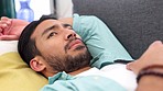 Depression, stress and man holding phone on a sofa, waiting for a text, email or answer while looking sad in living room. Anxiety, worry and unhappy asian male feeling numb after breakup text message