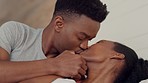 Couple, love and kiss with a man and woman kissing in bed in the bedroom of their home together. Happy, smile and romance with a young male and female being intimate, romantic and bonding in a house