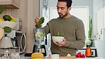Man makes a healthy lunch in kitchen with fruit and vegetables for a fresh smoothie. A positive lifestyle starts with eating well, exercising for physical wellbeing and working on your mental health 