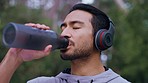 Water, music and workout with a sports man training outdoor in the forest or woods for fitness and wellness. Exercise, sport and motivation with a young male athlete listening to audio while running