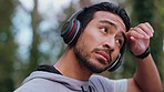 Fitness exercise, runner rest on outdoor cardio workout and green forest in Canada. Healthy latino man training in woods, listening to music with headphones and athlete wipe sweat from forehead
