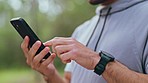 Mobile app fitness, reading social media and man training with phone in nature, motivation on technology for runner and communication while running in summer. Hands of athlete on web during workout