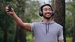 Phone, exercise and man in forest selfie record journey, adventure or travel in countryside woods. Training, runner and health fitness influencer with headphones relax and streaming nature jog online