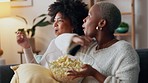 Movie, lgbt couple and girlfriends with popcorn fight for remote to change channel. Black woman and friend on sofa watching tv. Relax, laugh and pride, happy women in living room for fun date night.