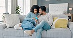 Couple on the sofa with phone on the internet together. Multicultural, black woman and asian man online, on social media and browsing for streaming a movie at home. Young people using a smartphone