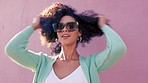 Cool black woman afro, sunglasses and fashion in fun summer style against a pink wall background. Portrait of a happy attractive African female smiling in stylish glasses, curly hair and urban look