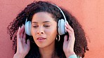 Music headphones, city dancing and black woman listening to audio on radio, happy with online podcast and smile for freedom against red wall in summer. Face of African girl streaming dance song