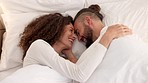 Man, woman and bed love bonding, smile and laughing at funny comedy, comic or goofy joke together in house. Silly, romance and happy young couple touch face, beard and wake up in apartment bedroom