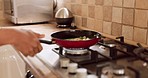 Man cooking food in the kitchen at his home with ingredients on a gas stove for dinner or lunch. Chef frying or preparing vegetables for a healthy, organic and vegetarian dish in a pan at his house.