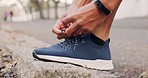 Man ties the shoelace on his sneakers before running and exercise. Runner tying running shoes on the side walk or pavement of the road, getting ready to go for a run. Fitness, training and cardio